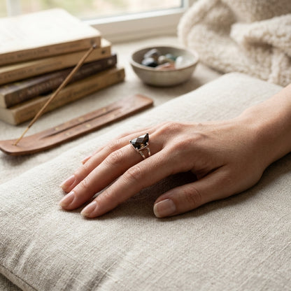 Size 8 Smokey Quartz grounding ring worn on a middle finger in a tranquil meditation setting with natural light.