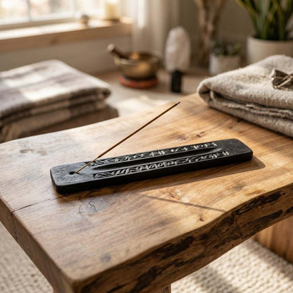 Petite carved black ash catcher with incense hole, used in meditation and spiritual rituals, on a wooden table in a serene space.