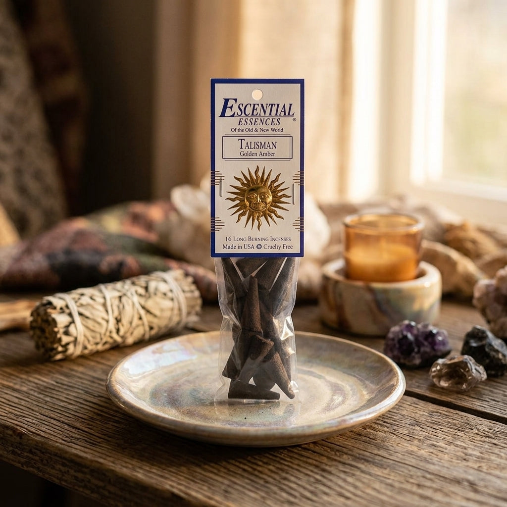 Small golden amber incense cone on a textured ceramic dish, with grounding elements like crystals and sage in a serene setting.