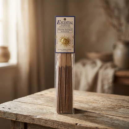 Photorealistic scene of a 16-pack of Winter Solstice incense sticks on natural wooden surface with warm lighting and rustic background.